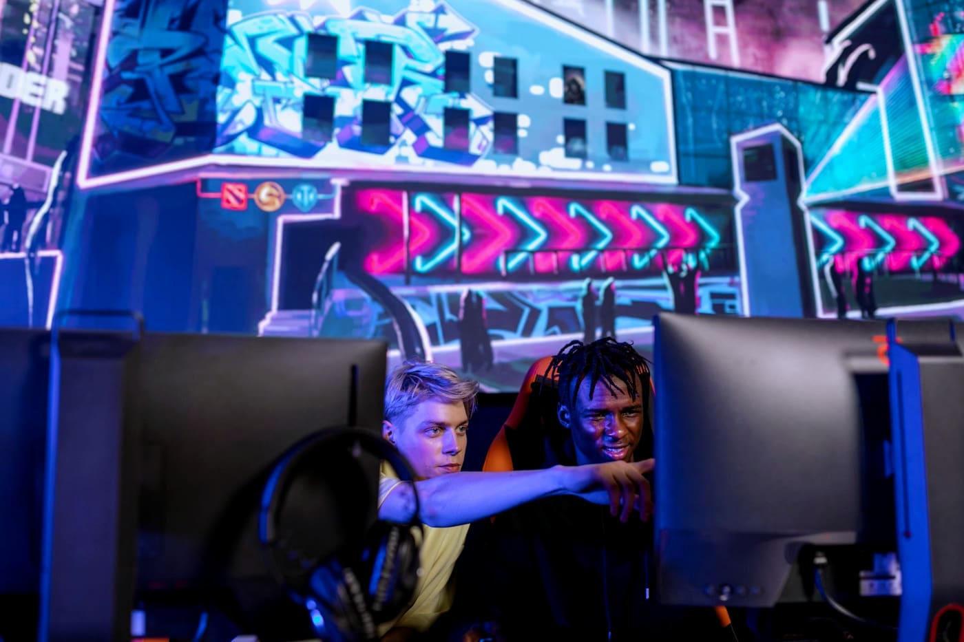 A coach pointing out details on a player's screen during a gaming session